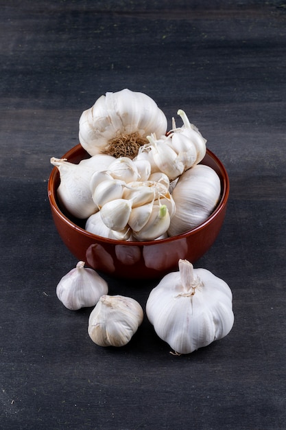 bunches of garlic in bowl on dark wooden table