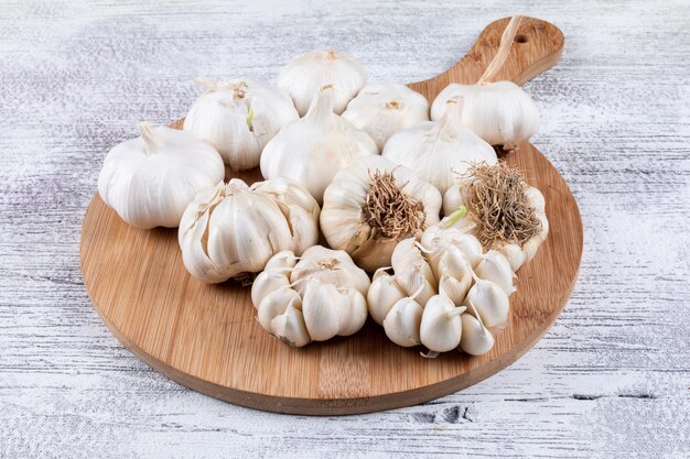 Bunches of garlic on cutting board on a light wooden table