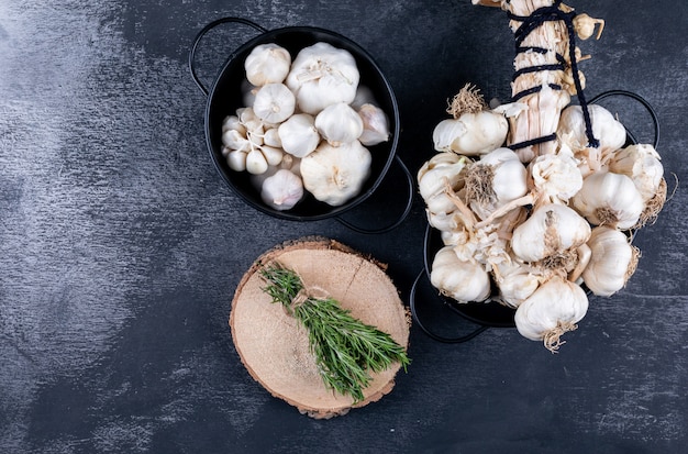 Bunches of garlic and rosemary with some of it in a bucket top view