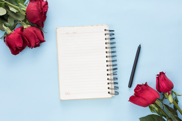 Bunches of red flowers near notebook and pen