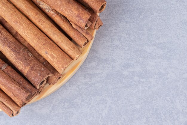 Bundle of cinnamon sticks on a small platter on marble table.