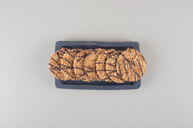 Bundle of cookies on a wooden platter on marble background.