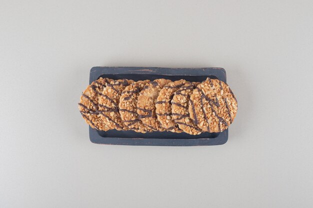 Bundle of cookies on a wooden platter on marble background.