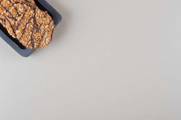 Bundle of cookies on a wooden platter on marble background.