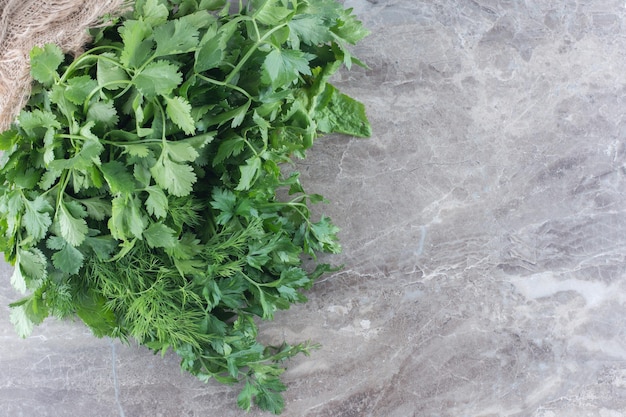 Bundle of coriander and dill on marble surface