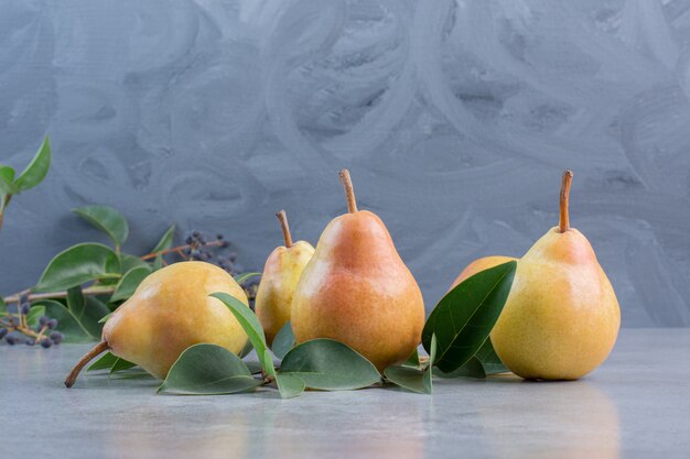 Bundle of leaves and pears on marble background. 
