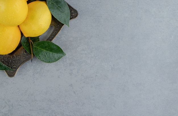 Free photo bundle of lemons and leaves on an ornate tray on marble