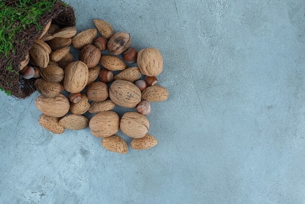 Bundle of nuts pouring out of a fancy bowl on marble.