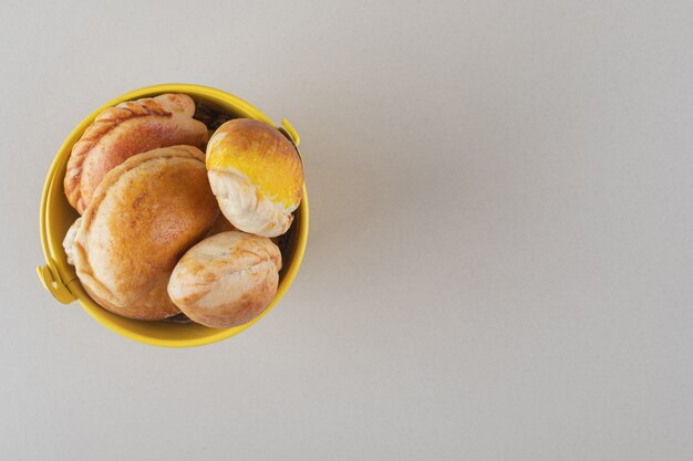 Bundle of small buns in a bucket on marble background.