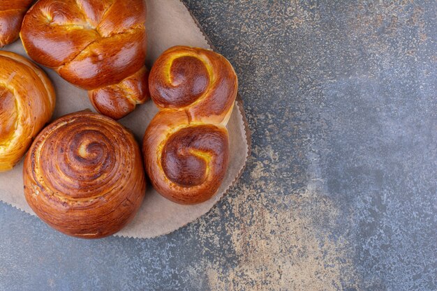 Bundle of sweet buns on a wooden board on marble surface