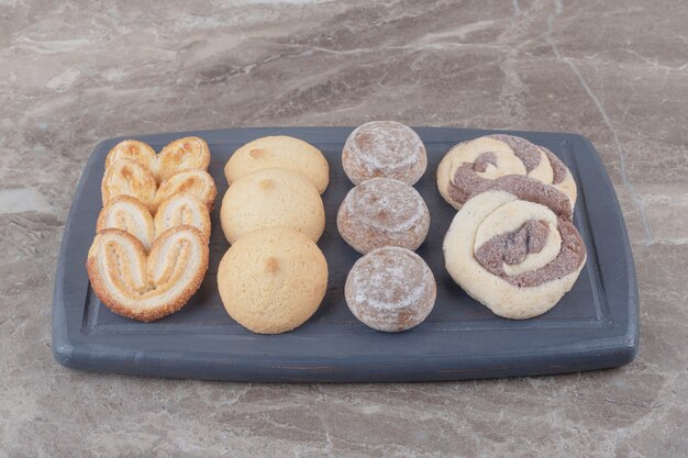 A bundle of various cookies on a board on marble