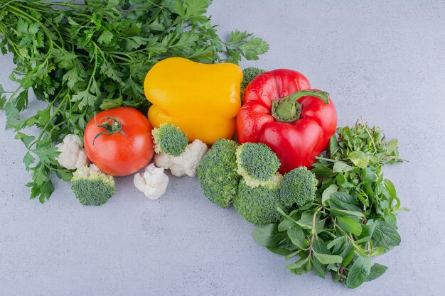 Bundle of vegetables and greens on marble background.