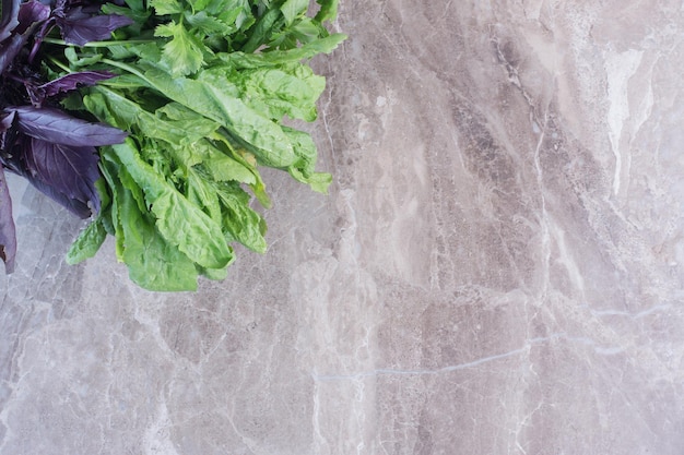 Free photo bundles of basil and amaranth on marble surface