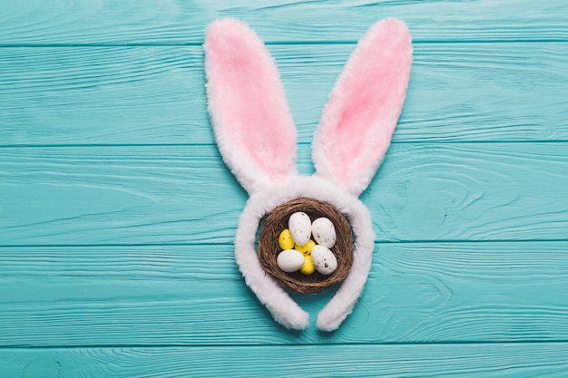 Bunny ears and nest on wooden background