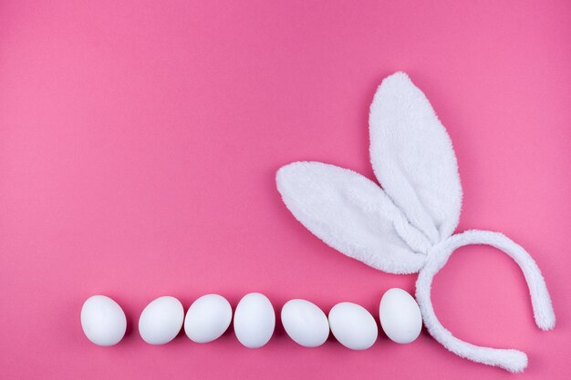 Bunny ears with white eggs on pink background