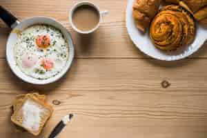 Free photo buns and coffee near fried eggs and toasts