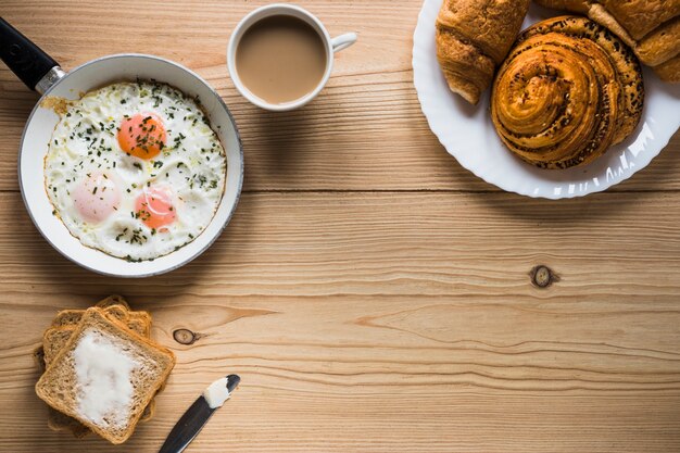 揚げた卵とトーストの近くのパンとコーヒー