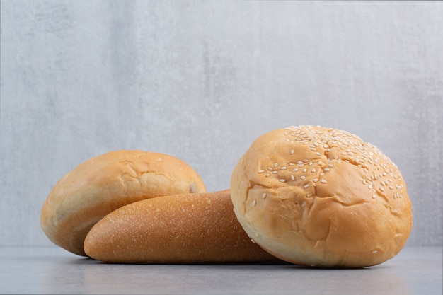 Buns and loaf bread on stone surface