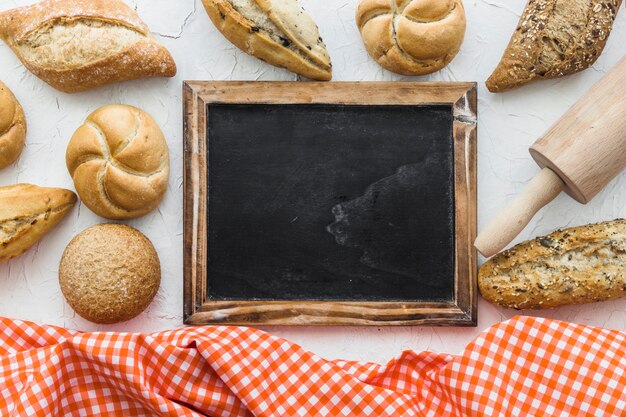 Buns and rolling pin near blackboard and fabric