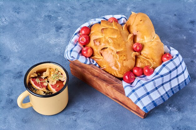 Buns with drink on a wooden board on blue