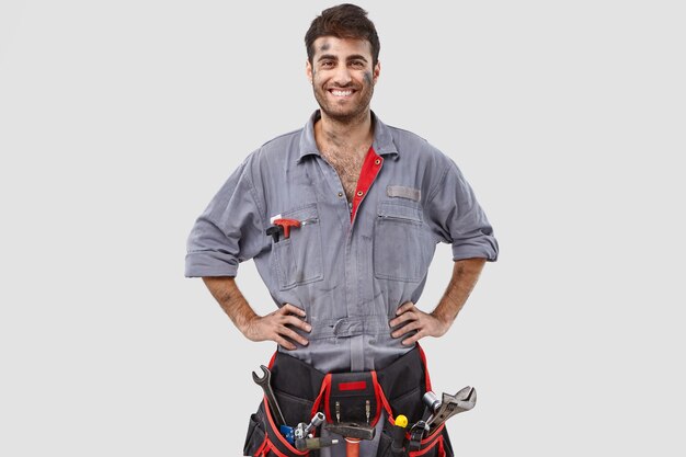 Buoyant successful handyman posing against the white wall