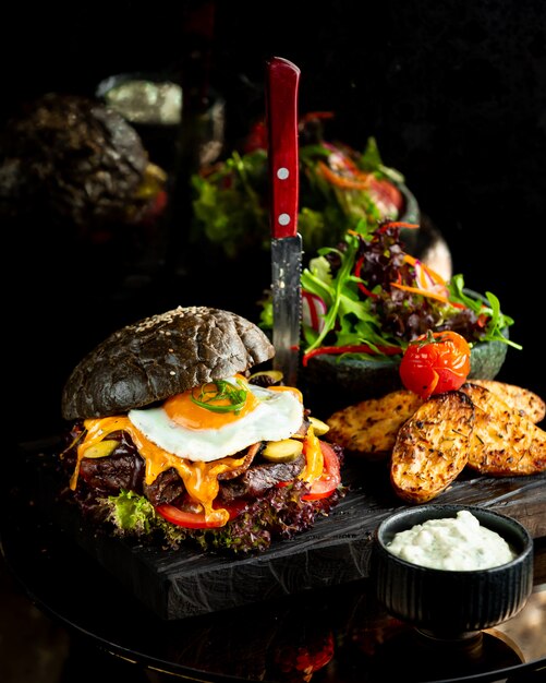 Burger in black bread bun with fried egg.