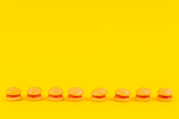 Burger candies in a row on yellow surface