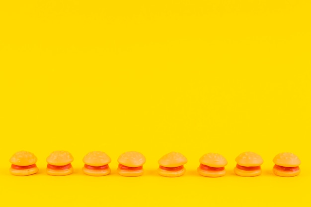 Burger candies in a row on yellow surface