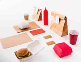 Free photo burger; disposal cup; sauce bottle and food parcel on white backdrop