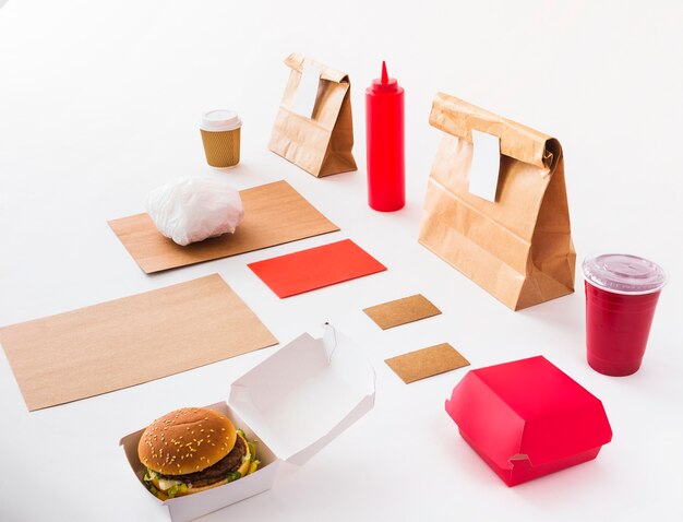 Burger; disposal cup; sauce bottle and food parcel on white backdrop