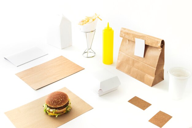 Burger; french fries; sauce and paper package on white backdrop