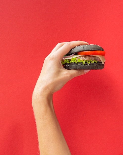 Free photo burger held in front of red background