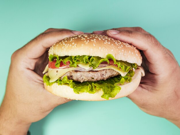 Burger held over turquoise background