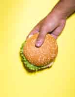 Free photo burger held over yellow background