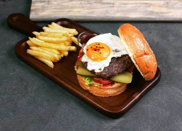 Burger with fried egg, meat and vegetables.