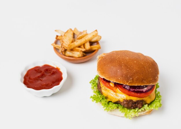 Burger with fries and ketchup on white table