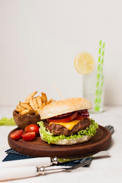 Burger with fries on wood plate