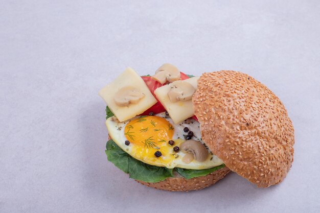 Burger with omelet, tomatoes, mushrooms and onion.