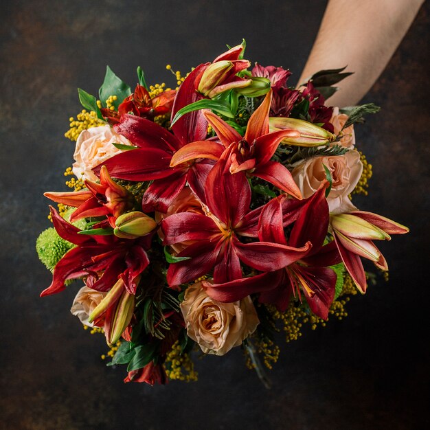 Burgundy and orange lillian bouquet with roses in dark background