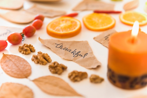 Burning candle near notes, fruits and leaves 