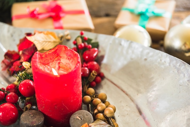 Burning candle on plate near present boxes