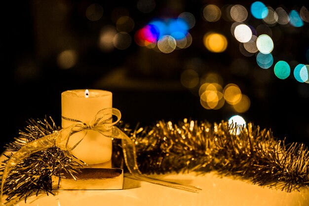 Burning candle with bow and tinsel