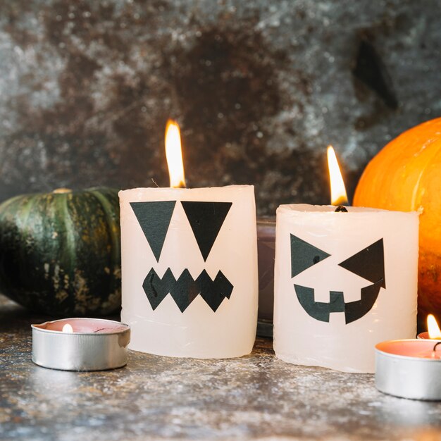 Burning candles in Halloween style standing with pumpkins on background
