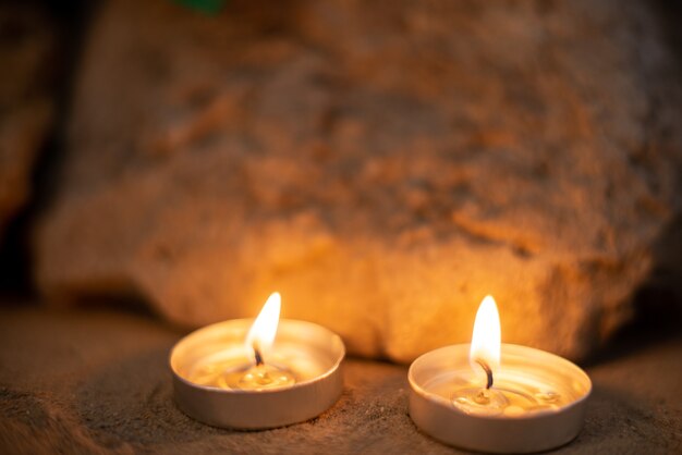 Burning candles on sand as memory funeral death