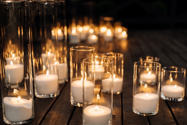 Burning candles in the transparent glass candlestick on the floor