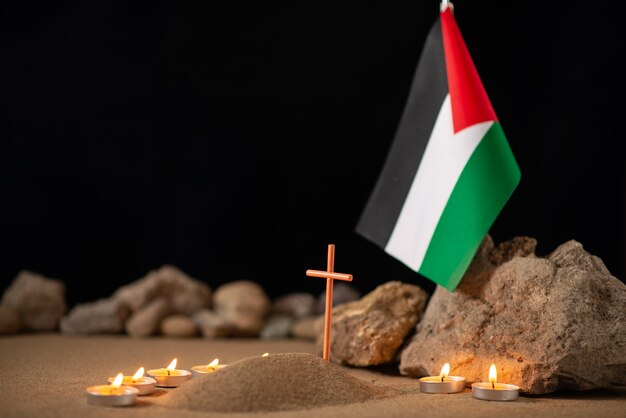 Burning candles with palestinian flag around little grave