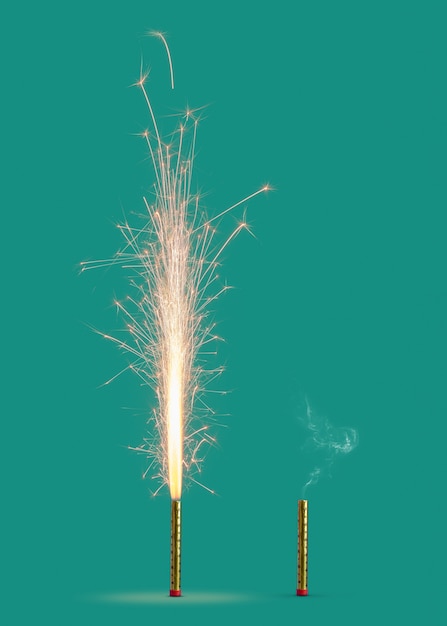 ターコイズブルーの背景に明るい火花と燃えたろうそくからの煙で燃える花火 コピースペース お祭りイベントのコンセプト プレミアム写真