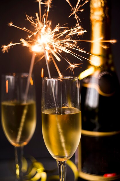 Burning sparkler in champagne glass on dark background