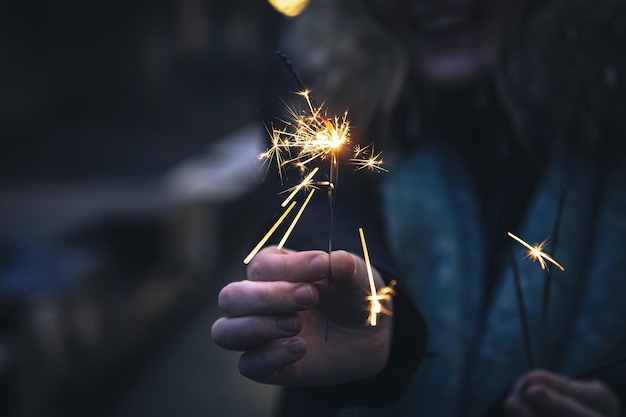 Burning sparklers in the hands of a young woman in the dark