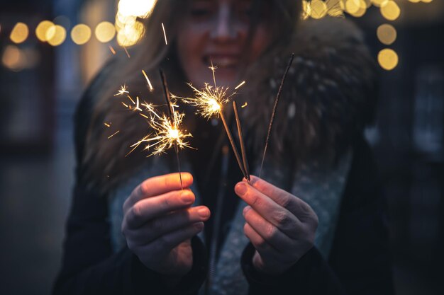 Burning sparklers in the hands of a young woman in the dark